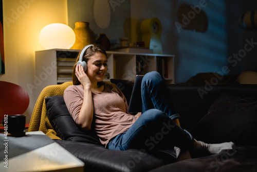 woman relaxing at home using digital tablet and listening music