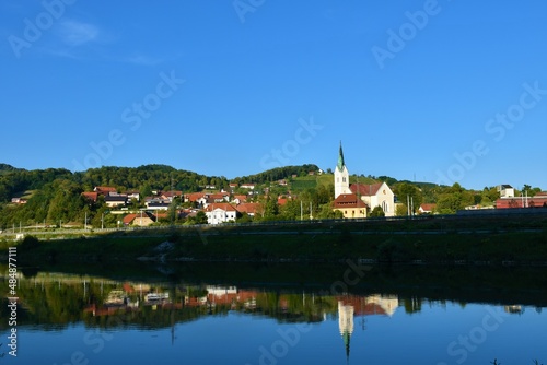 View of the town of Krsko in Dolenjska  Slovenia with Sava river in front and forest covered hills behind and a reflection in the water