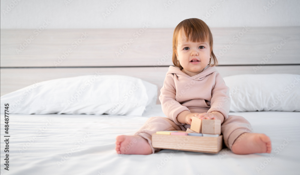 little cute kid playing with toy cubes sitting on bed at home. little cute kid playing with toy cubes sitting on bed at home.