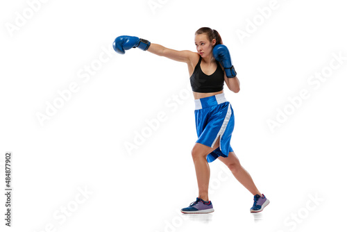Dynamic portrait of young girl, professional boxer practicing in boxing gloves isolated on white studio background. Concept of sport, studying, competition
