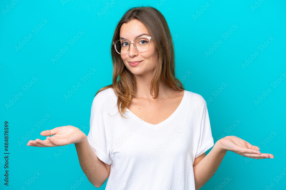 Fototapeta premium Young caucasian woman isolated on blue background With glasses and having doubts