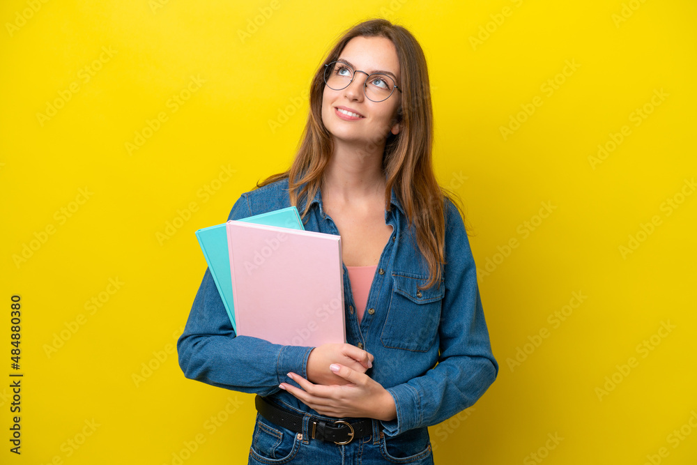 Young student caucasian woman isolated on yellow background thinking an idea while looking up Young student caucasian woman isolated on yellow background thinking an idea while looking up