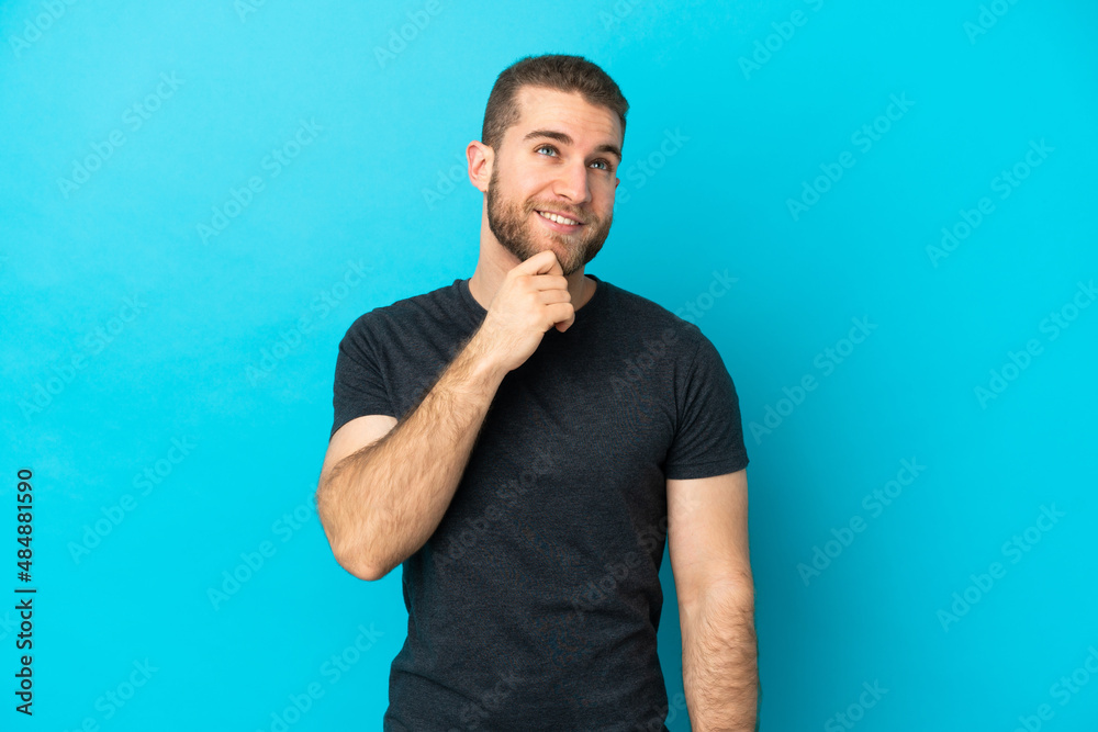 Young handsome caucasian man isolated on blue background and looking up Young handsome caucasian man isolated on blue background and looking up