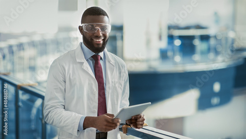 Happy young black medical scientist using digital tablet