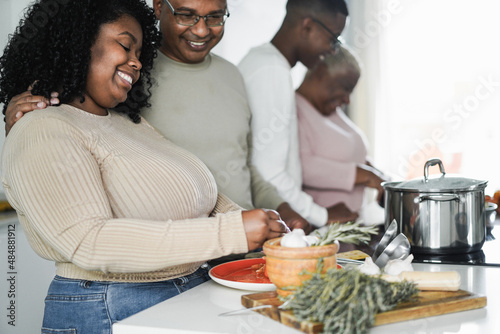 Happy black family cooking inside kitchen at home - Focus on daughter face