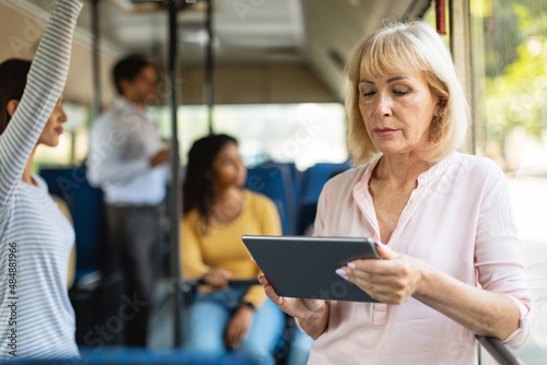 Portrait of senior woman taking bus using tablet