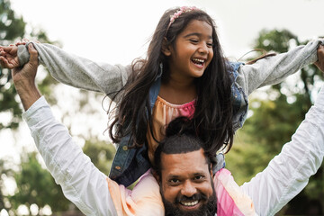 Happy indian father having fun with her daughter outdoor - Focus on father face