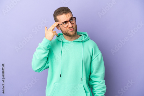 Young handsome caucasian man isolated on purple background with problems making suicide gesture © luismolinero