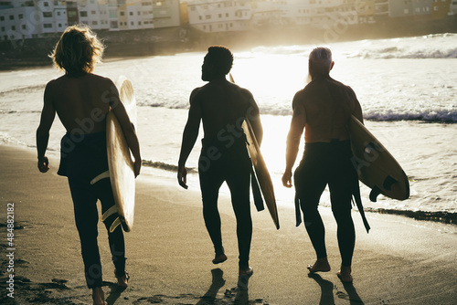 Photography Multi generational surfer friends having fun while surfing on beach - Focus on l