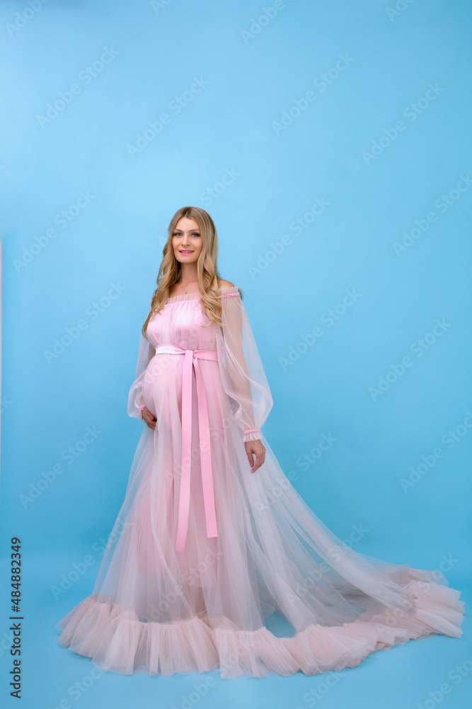 pregnant woman in a pink dress on a blue background with a white flower pregnant woman in a pink dress on a blue background with a white flower