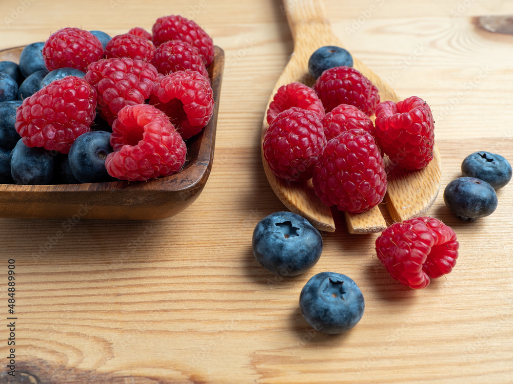 Raspberries and blueberries on a wooden background. Raspberries and blueberries on a wooden background.