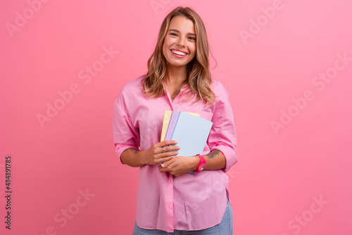 blond pretty woman in pink shirt smiling holding holding notebooks