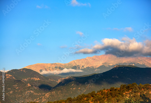 image of sunrise striking Pikes Peak in Colorado as low lying clouds hover near the mountain