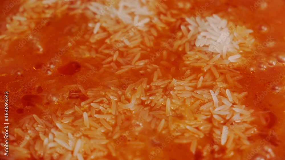 Jollof rice cooking. Rice with tomato paste, tomatoes, spices is cooked in a pan. Close-up. Jollof rice cooking. Rice with tomato paste, tomatoes, spices is cooked in a pan. Close-up.