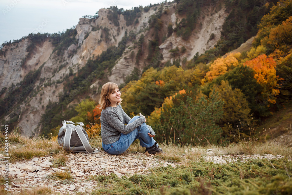 Fototapeta premium Woman having a break, resting during hiker tour, beautiful forested mountains view in the background