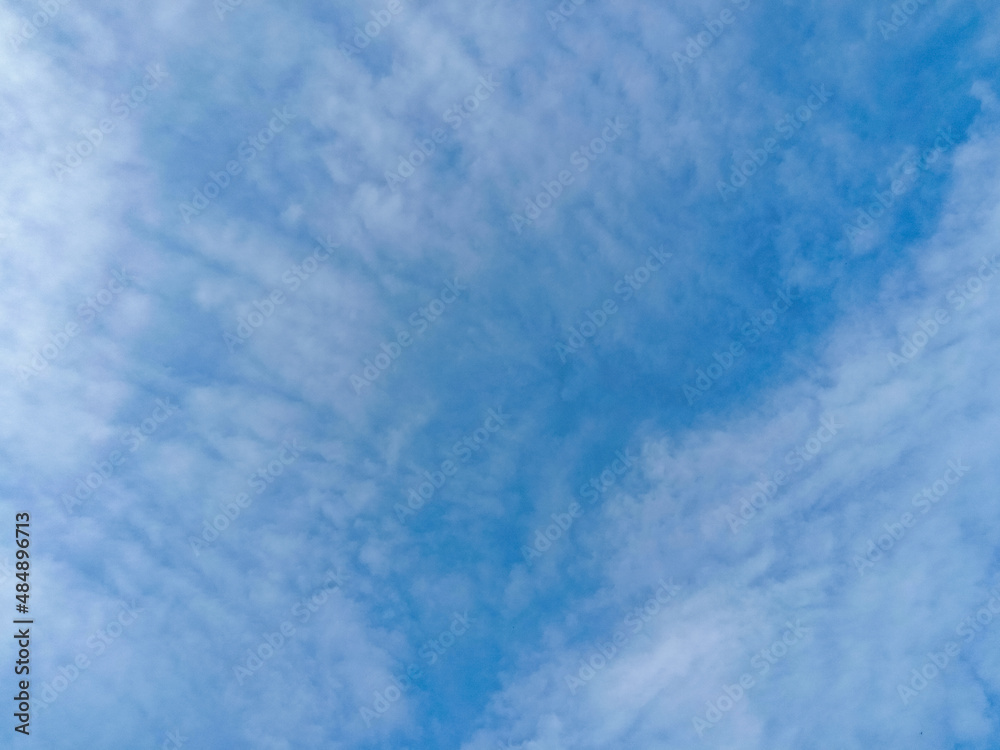 Elegant Cloudy Blue Sky texture, wallpaper background. Beautiful deep blue sky with rounded small soft white clouds in daylight. Landscape image. Altocumulus clouds (Small rows of fluffy ripples).
