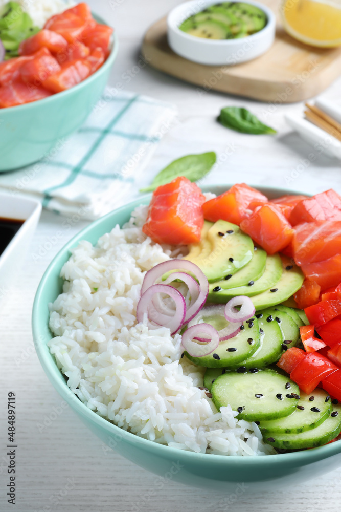 Delicious poke bowl with salmon and vegetables served on white wooden table Delicious poke bowl with salmon and vegetables served on white wooden table