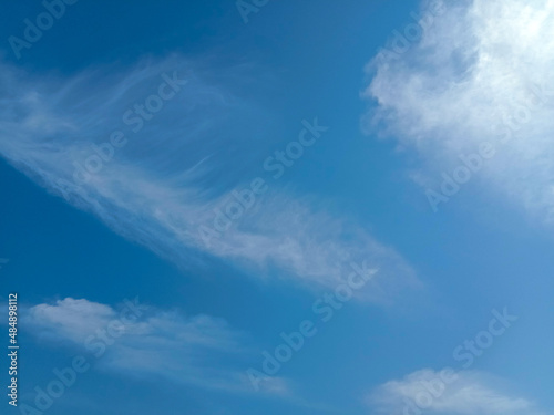 Cloudy blue sky background. Beautiful blue sky with wispy fluffy soft white clouds in daylight. Elegant cloudy clear blue sky texture  wallpaper. Horizontal landscape image. Cirrus Clouds. No focus