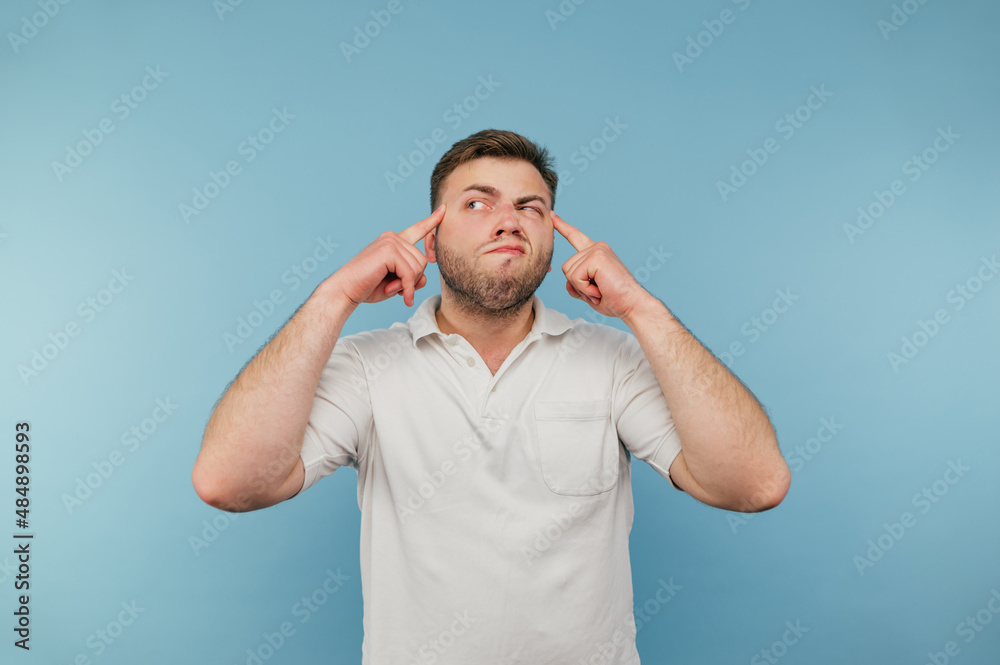 Funny man with a beard shows his fingers on his temple and looks away with a serious face. Funny man with a beard shows his fingers on his temple and looks away with a serious face.