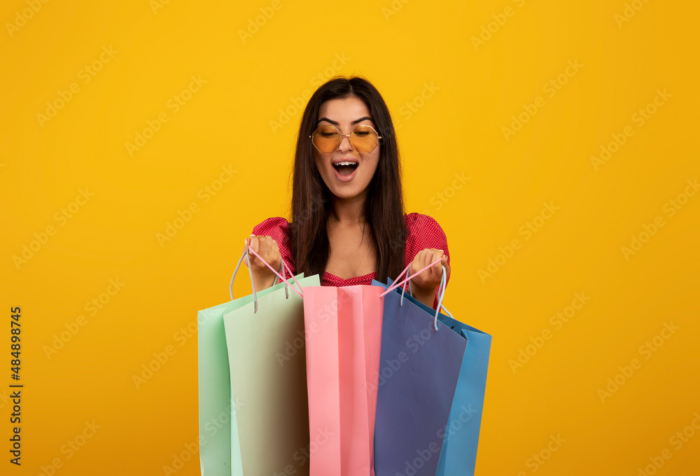 Satisfied customer. Excited armenian woman looking inside bright shopping bags, happy with her purchases Satisfied customer. Excited armenian woman looking inside bright shopping bags, happy with her purchases