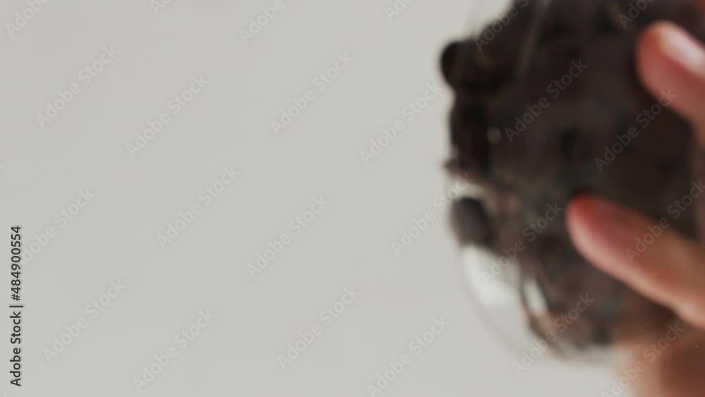 Bottom view of dark chocolate chips falling from a bowl on a transparent background and filling up the entire space. Chocolate chips falling on camera. Cooking.