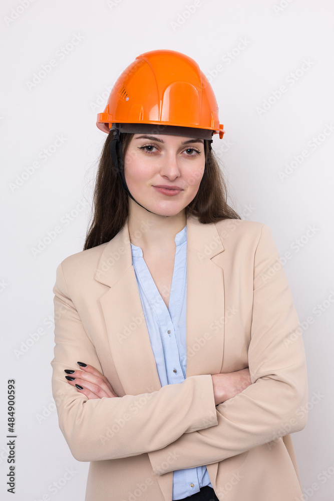 A girl architect in a suit and an orange construction helmet stands on a white background. A girl architect in a suit and an orange construction helmet stands on a white background.
