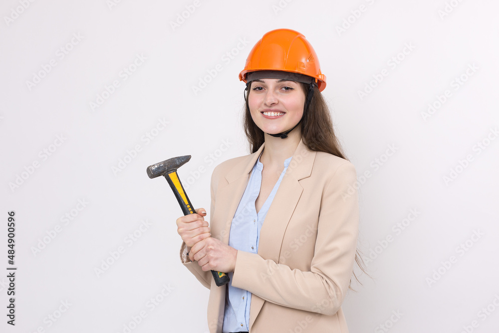 Girl engineer in an orange construction helmet with a hammer on a white background. Girl engineer in an orange construction helmet with a hammer on a white background.
