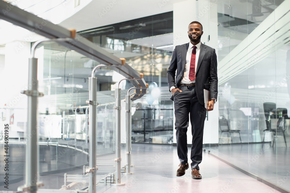 Positive black manager walking by office building Positive black manager walking by office building