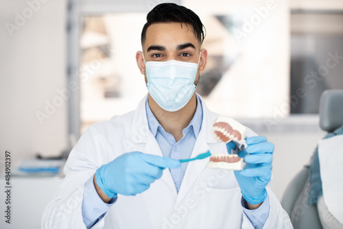 Oral and Dental Health. Arab Dentist Doctor Holding Jaw Model And Toothbrush