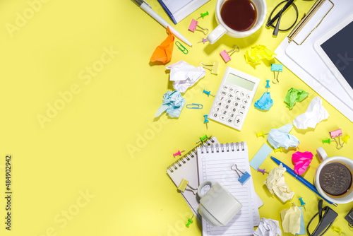 Brainstorming office table background. Office work table with notepads, pens, pencils, crumpled colorful paper, office supplies. Creative business team brainstorming concept flatlay yellow background 
