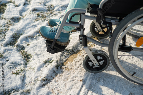 Fototapeta Naklejka Na Ścianę i Meble -  Close-up of legs of woman in wheelchair in winter outdoors. 