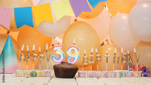 Happy birthday greetings for 39 years old from golden letters of candles burning against the background of mine space balloons. Beautiful birthday card with a muffin for thirty nine years photo