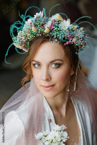 Large portrait of a beautiful bride with a wedding hairstyle and makeup with a veil and a wreath of flowers. Morning of the bride.