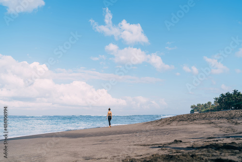Scenic horizontal view of morning time at seaside with water and sandy beach, young female traveller in sportive tracksuit exploring touristic landscape of ocean during vacations at exotic island