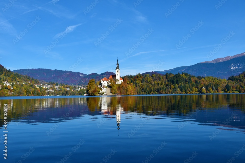Scenic view of the church of the assumptin of Mary on an island on Bled lake in Gorenjska, Slovenia in autumn with a reflection of the church in the water