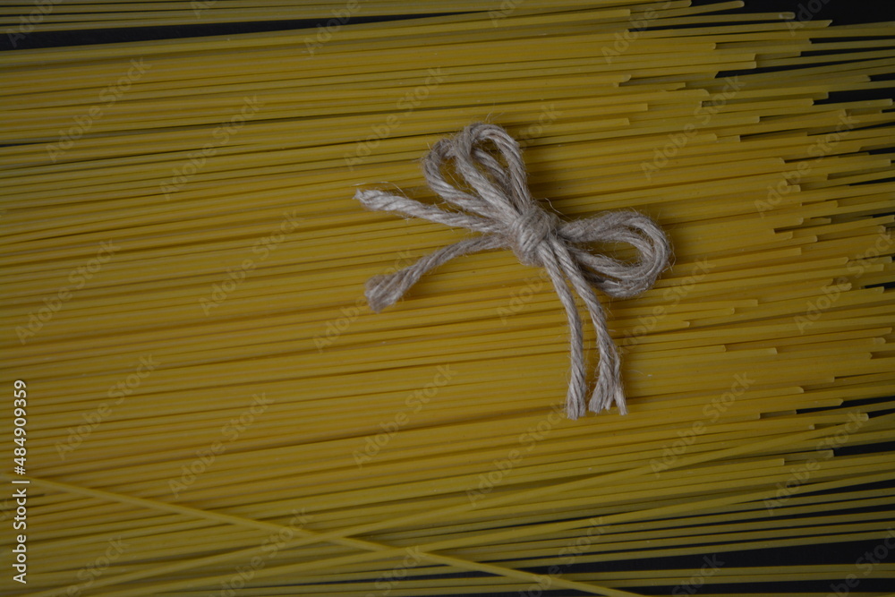 Raw spaghetti wrapped with rope on a black background, close up. High quality photo Raw spaghetti wrapped with rope on a black background, close up. High quality photo