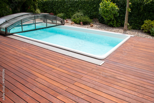 Outdoor swimming pool with cover enclosure and teak wood deck