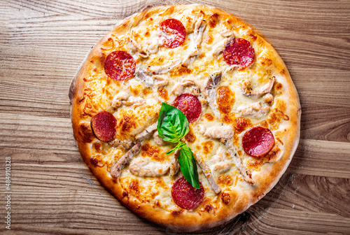 Pizza with Mozzarella cheese, salami, ham, Tomato sauce, pepper, spices. Italian pizza on wooden background