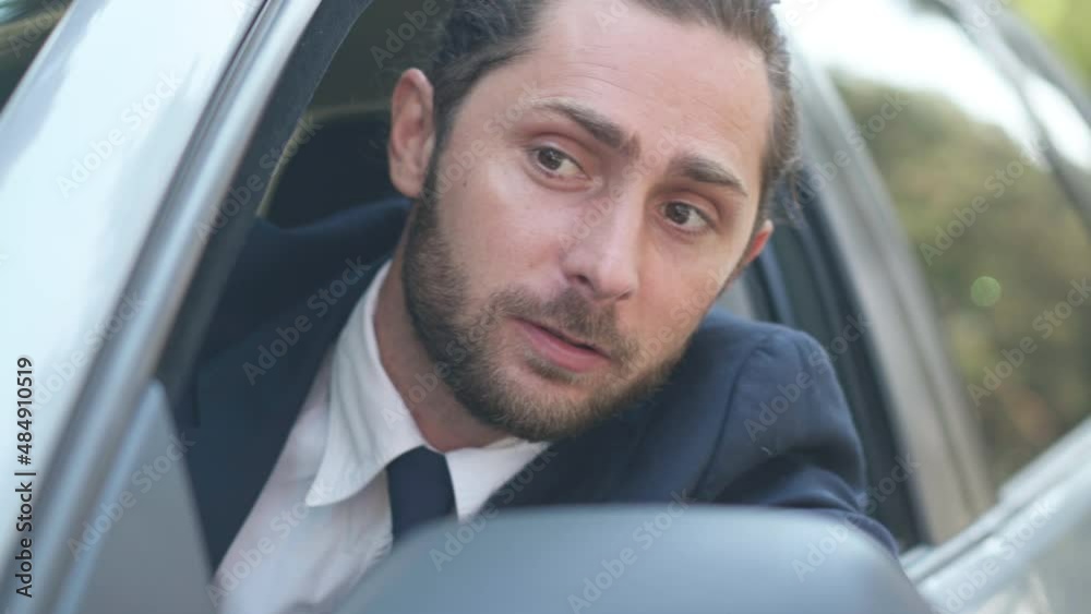 Close-up angry male young driver leaning out car window shouting gesturing looking away. Portrait of dissatisfied Caucasian handsome man arguing in traffic jam outdoors. Stress and lifestyle Close-up angry male young driver leaning out car window shouting gesturing looking away. Portrait of dissatisfied Caucasian handsome man arguing in traffic jam outdoors. Stress and lifestyle