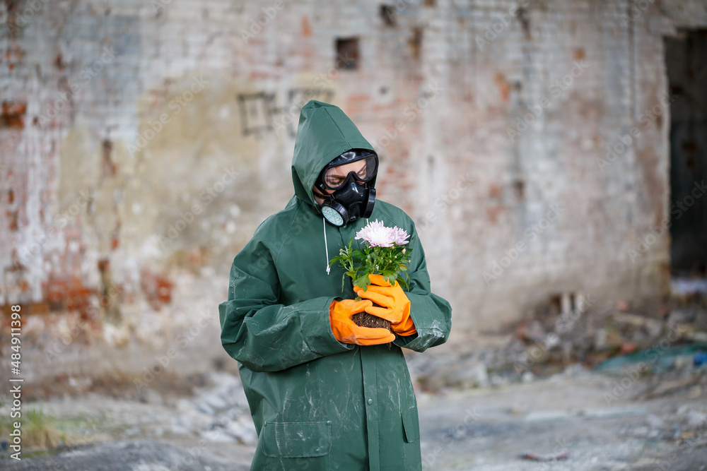 Obraz premium A dosimetrist scientist radiation inspector in protective clothing and a gas mask examines the danger zone. Close-up. Flower. Ecological catastrophy