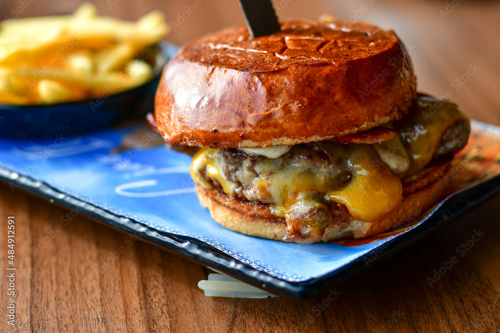 Delicious Beef Burger with bacon, cheddar ,egg and home made french fries from organic potatoes on wooden table Delicious Beef Burger with bacon, cheddar ,egg and home made french fries from organic potatoes on wooden table