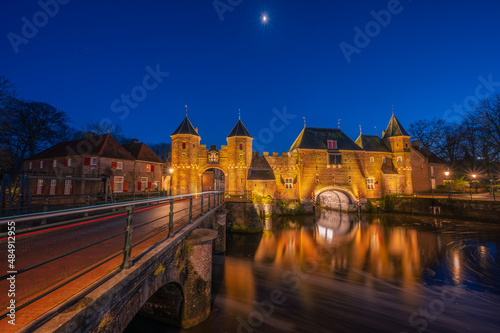 An old medieval gate called the Koppelpoort in Amersfoort with a beautiful reflection and traffic lights during the blue hour