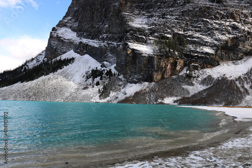 The shore of the icy lake is surrounded by Rocky Mountains