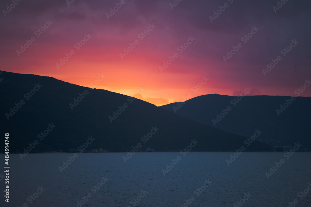 Colorful Sunset on Clear Sky, Sun Setting in Mountain Range by the Sea. Background. Copy space. High quality photo