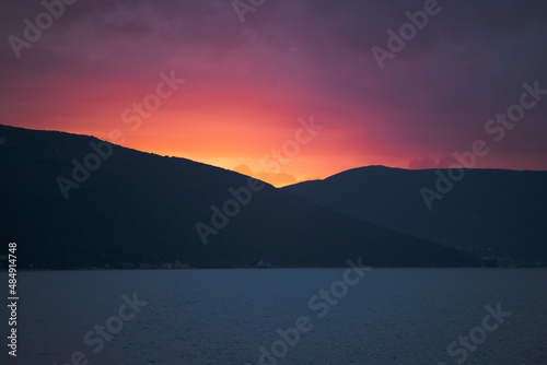 Colorful Sunset on Clear Sky, Sun Setting in Mountain Range by the Sea. Background. Copy space. High quality photo