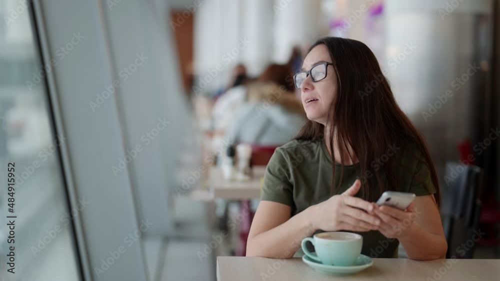 inspired woman in cafe, viewing social nets in smartphone and drinking hot coffee inspired woman in cafe, viewing social nets in smartphone and drinking hot coffee