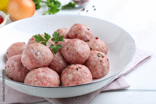 Many fresh raw meatballs on white wooden table, closeup