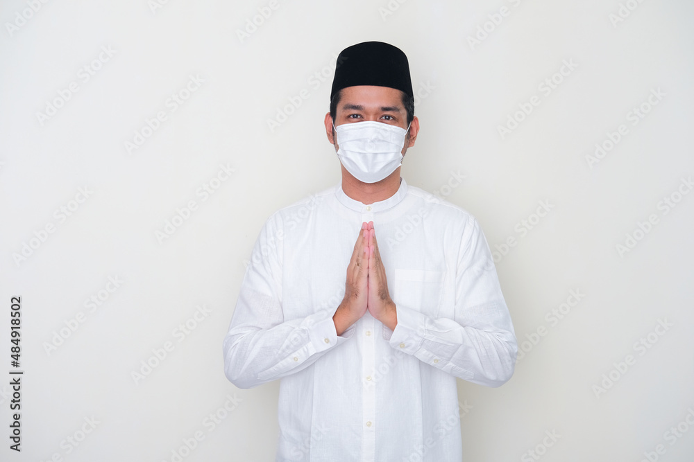 Moslem Asian man greeting pose and wearing medical mask to celebrate Ramadan during pandemic
