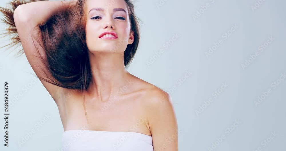 Passionate about haircare. 4k video footage of a beautiful young woman playing with her hair in the studio.