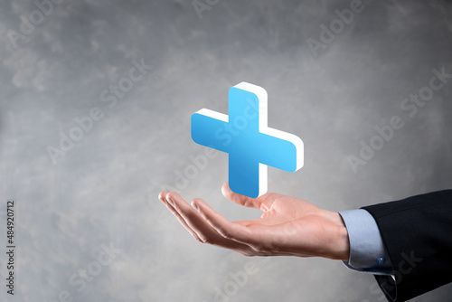 Businessman hold 3D plus icon, man hold in hand offer positive thing such as profit, benefits, development, CSR represented by plus sign.The hand shows the plus sign